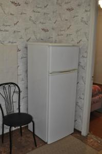 einen weißen Kühlschrank in einem Zimmer mit Stuhl in der Unterkunft Apartment near the bus station in Kremenchuk in Krementschuk