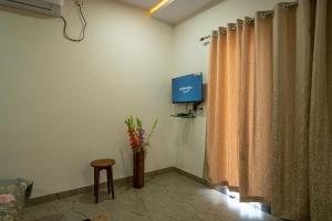 Habitación con TV, cortina y mesa. en Takshshila Park And Resorts en Jagdalpur