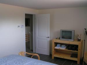 1 dormitorio con 1 cama y mesa con TV en Nowak's Own B&B en Shediac