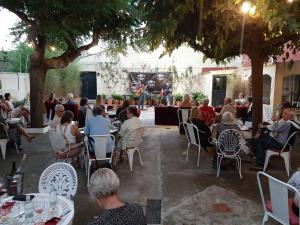 a group of people sitting at tables in a patio with a concert at Hostal Plaja i Pati de Can Plaja in Palafrugell