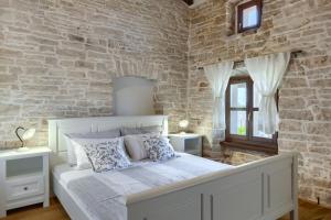 Un dormitorio con una cama blanca y una pared de piedra. en Villa Paulina -an authentic sense of Istrian life, en Gajana 69 fotos más