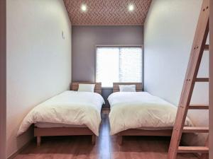 Duas camas num quarto com uma janela em YADOYA 入谷庵 em Tóquio