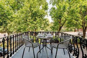 a table and chairs on a balcony with trees at Buckingham & Lloyds in London