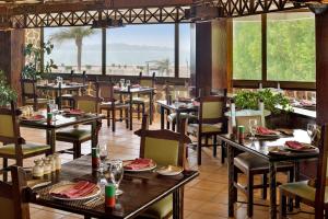 uma sala de jantar com mesas, cadeiras e janelas em Al Corniche em Jidá