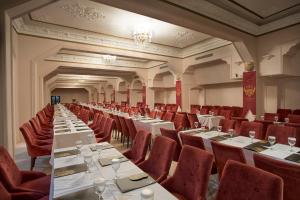 a large room with white tables and red chairs at Le Chateau Lambousa in Kérynia