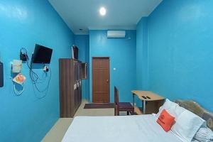 a blue room with a bed and a table and a chair at KoolKost Syariah At Komplek PLN Balikpapan in Balikpapan
