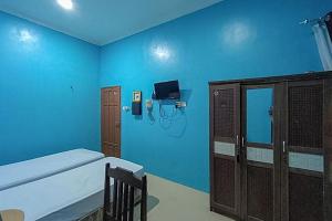 a blue room with a bed and a tv in it at KoolKost Syariah At Komplek PLN Balikpapan in Balikpapan