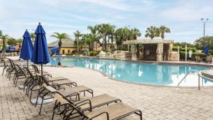 einen Pool mit Stühlen und Sonnenschirmen in einem Resort in der Unterkunft Townhome w pool near Disney & Orlando Attractions in Kissimmee