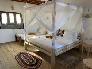 een slaapkamer met 2 bedden en een hemelbed bij Sweet Beach Apartments in Jambiani