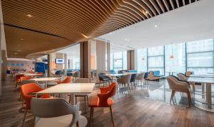 深セン市にあるHoliday Inn Express Shenzhen Longhua by IHGのテーブルと椅子と窓のあるレストラン