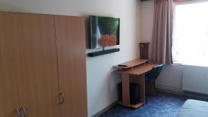 Habitación de hotel con escritorio y TV en la pared en Panoráma Apartmanház, en Esztergom