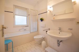 ein weißes Badezimmer mit Toilette und Waschbecken in der Unterkunft Ferienwohnung Sanddorn - Strandhaus Lobbe in Lobbe