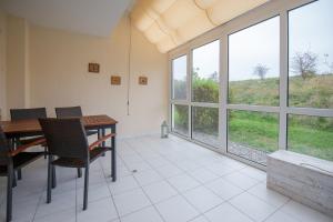 comedor con mesa, sillas y ventanas en Ferienwohnung Sanddorn - Strandhaus Lobbe, en Lobbe