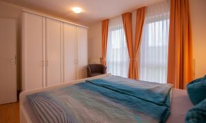 ein Schlafzimmer mit einem Bett und einem Stuhl neben einem Fenster in der Unterkunft Ferienwohnung Sanddorn - Strandhaus Lobbe in Lobbe