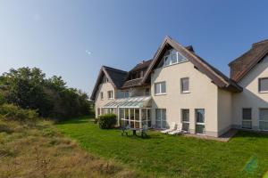 ein großes weißes Haus mit einem Rasenplatz in der Unterkunft Ferienwohnung Sanddorn - Strandhaus Lobbe in Lobbe