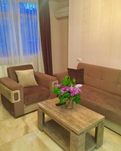 MG Apartments in Tbilisi في تبليسي: غرفة معيشة مع أريكة وطاولة مع زهور