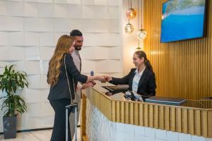 un uomo e una donna che stringono la mano a un bancone di Flamant Rose Appart Hotel a Tangeri