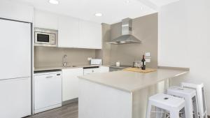 a white kitchen with white cabinets and white stools at 1 I-58 - Calella de Palafrugell in Calella de Palafrugell