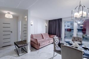 ein Wohnzimmer mit einem rosa Sofa und einem Tisch in der Unterkunft Resort Apartamenty Klifowa Rewal 72 in Rewal