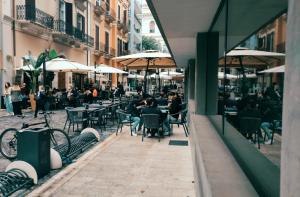 un grupo de personas sentadas en mesas en un café al aire libre en B&B Alighieri 97, en Bari