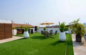 a patio with grass and white vases and a table and chairs at The Tivoli Hotel in Bangkok