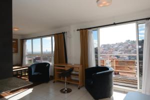 Cette chambre comprend deux chaises, un bureau et de grandes fenêtres. dans l'établissement Aina Hôtel, à Antananarivo