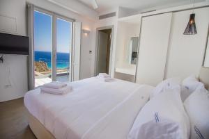 Dormitorio blanco con cama grande y vistas al océano en Anarina Villas & Suites Mykonos Elia Beach en Elia Beach