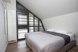 um quarto com uma cama branca e uma grande janela em Goudvink Egmond em Egmond aan den Hoef