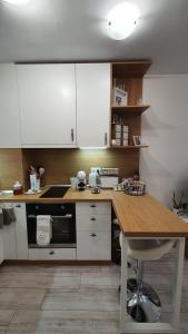 une cuisine avec des placards blancs et une table en bois dans l'établissement Borovets Cozy Mountain Apartments, à Borovets