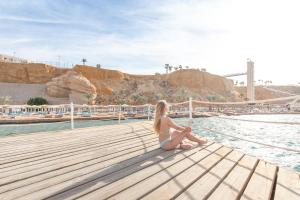 una mujer sentada en un muelle junto al agua en Albatros Sharm Resort - By Pickalbatros en Sharm El Sheikh