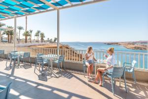 two women sitting on a balcony looking at the ocean at Albatros Sharm Resort - By Pickalbatros in Sharm El Sheikh