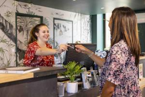 Deux femmes se tiennent au comptoir dans un salon dans l'établissement Hotel Les Suites - Domaine de Crécy, à Crécy-la-Chapelle