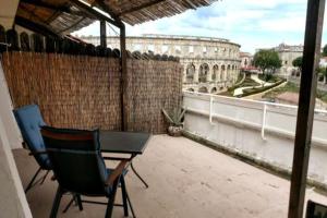 a balcony with a table and chairs and a view of a building at Terrace Dream View over Amphitheatre in Pula