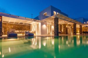 a swimming pool in front of a house at night at Anarina Villas & Suites Mykonos Elia Beach in Elia Beach