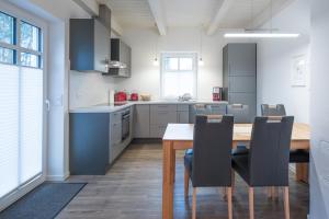 cocina con mesa de madera y sillas negras en Ferienhaus In de Bargen, en Langenhorn