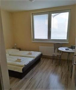 Schlafzimmer mit einem Bett, einem Tisch und einem Fenster in der Unterkunft Orava- Justína in Trenčianske Teplice