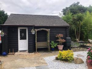 a black shed with a bench in a yard at Self catering private annex near Ferndown in Ferndown
