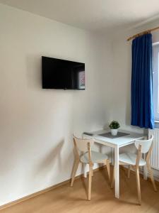 a room with a table and chairs and a tv on the wall at Ferienhaus Strandoase in Zingst