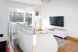ein Wohnzimmer mit weißen Möbeln und einem Fernseher in der Unterkunft Esnatuz - Basque Stay in San Sebastián
