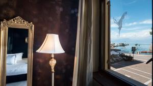 ペスキエーラ・デル・ガルダにあるOsteria Luxury Apartmentsのベッドルーム(ベッド1台、鏡、ランプ付)