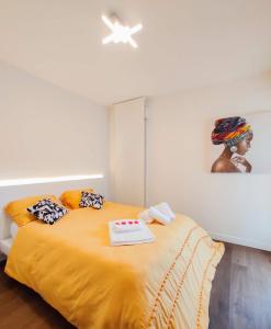 Un dormitorio con una cama amarilla con una pintura en la pared en T3 hypercentre avec terrasse et, parking, en Quimper