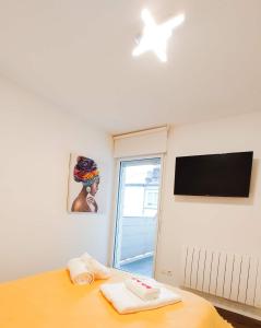 1 dormitorio con 1 cama, TV y ventana en T3 hypercentre avec terrasse et, parking, en Quimper
