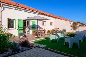 a patio with chairs and tables and an umbrella at Le Cabanon de Virginie in Salin-de-Giraud