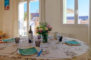 a table with a vase of flowers and a bottle of wine at Le Cabanon de Virginie in Salin-de-Giraud