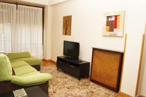 sala de estar con sofá y TV en Apartamento en el corazón de Gijón con parking incluido, VUT 78 en Gijón