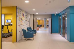 een kantoorgang met blauwe en gele muren en stoelen bij Domitys - La Majolique in Béziers
