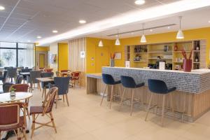een restaurant met een bar en tafels en stoelen bij Domitys - La Majolique in Béziers