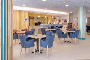 a dining room with tables and blue chairs at Domitys - La Majolique in Béziers