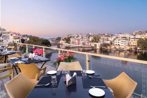a balcony with tables and chairs and a view of a city at Hotel Sarovar On Lake Pichola in Udaipur