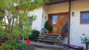 una casa con una puerta de madera y algunas flores en Ferienwohnung Hofmann, en Freudental